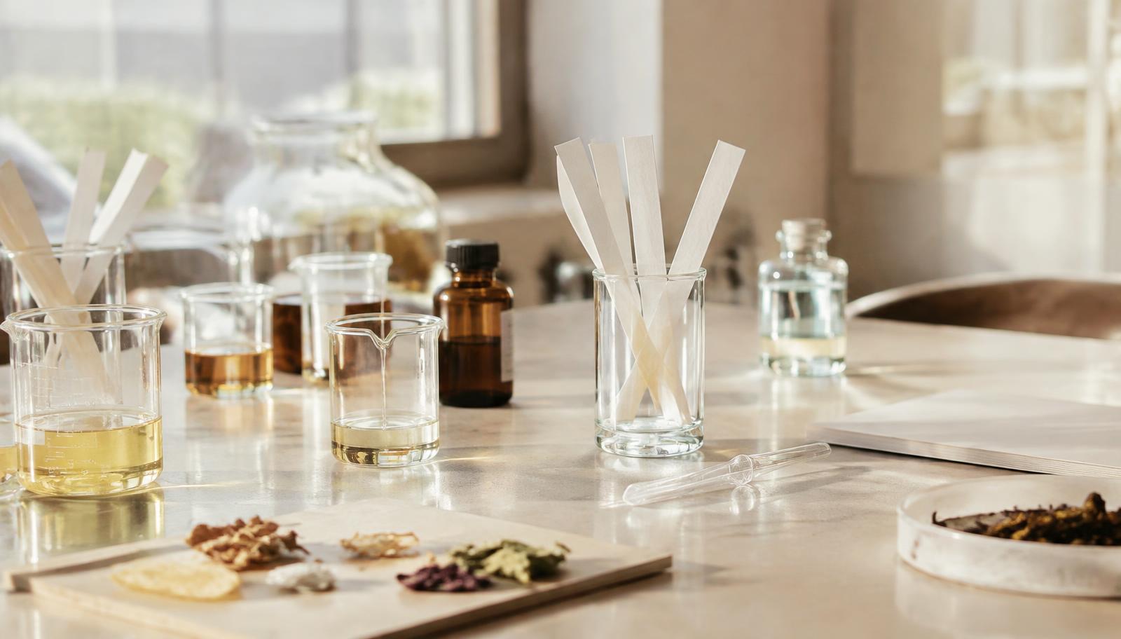 Bancada de desenvolvimento de fragrâncias com béqueres e fitas olfativas